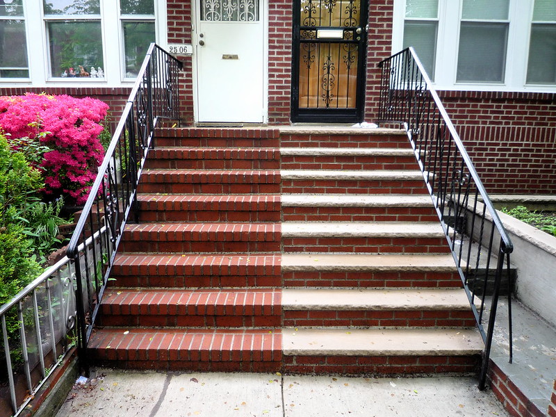 Treppe, die links und rechts aus unterschiedlichen Materialien gemacht ist, führt zu zwei optisch unterschiedlichen Hauseingangstürenn