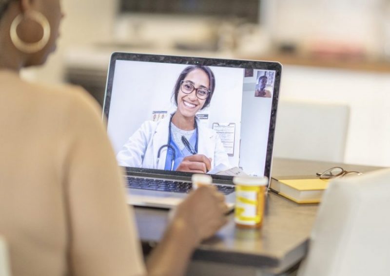 A woman consults a doctor on her laptop in a virtual care session.