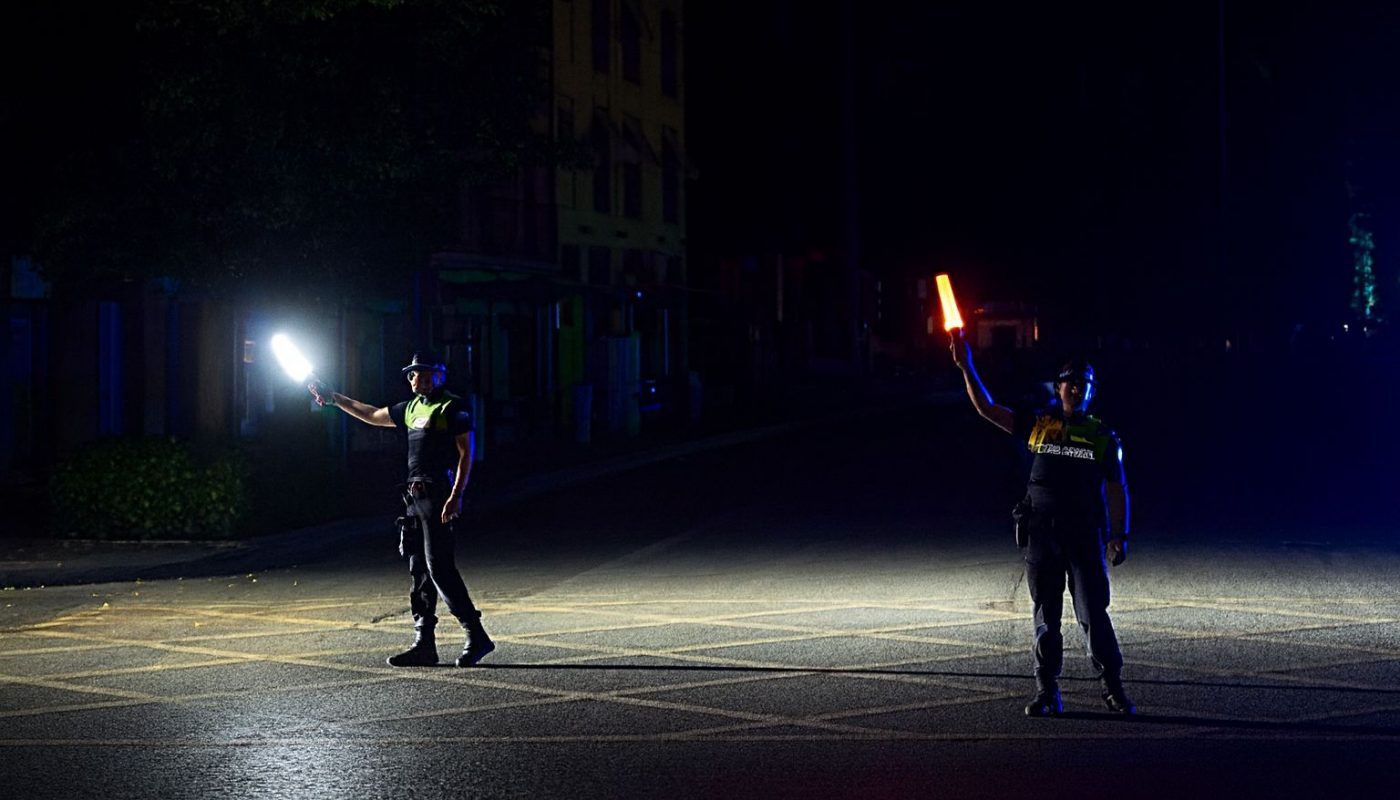 Zwei Polizisten regeln mit Stablampen den Verkehr in der Dunkelheit