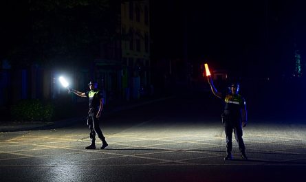 Zwei Polizisten regeln mit Stablampen den Verkehr in der Dunkelheit