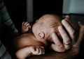 Ein Baby liegt geborgen in den Händen seines Vaters.