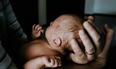 Ein Baby liegt geborgen in den Händen seines Vaters.