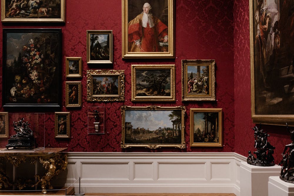  An image of a gallery wall of paintings in ornate frames with a description of the search query 'Fine art as an alternative investment'.