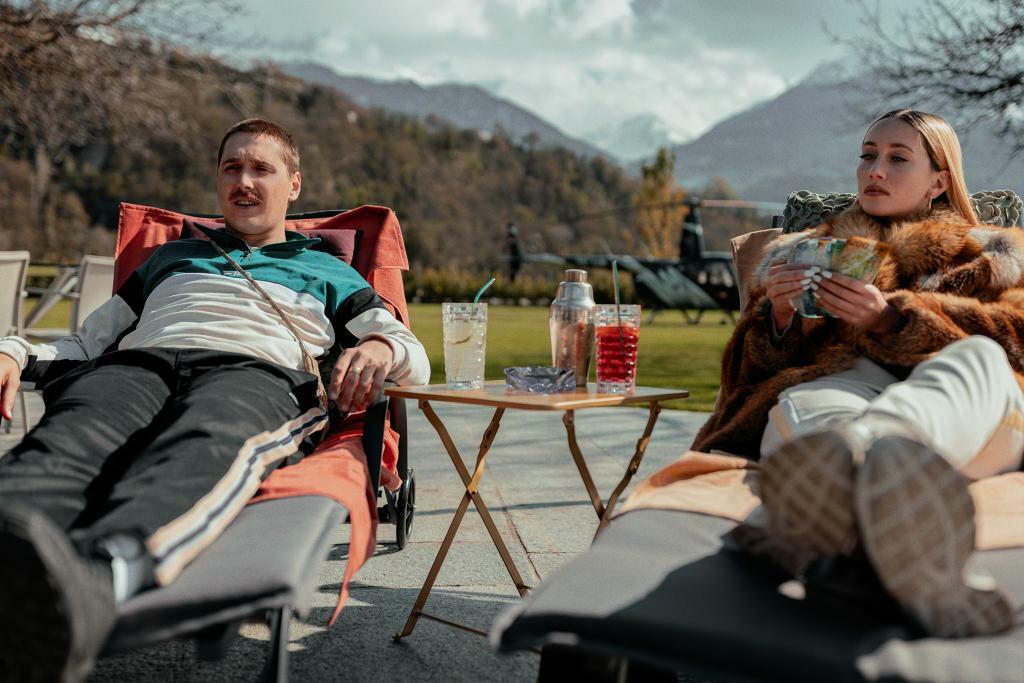 Juni und Valmira von der berühmten Walliser Serie "Tschugger" liegen auf Liegestühlen draussen, zählen Geld und trinken Cocktails.