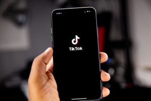 TikTok-App auf dem Smartphone einer Person geöffnet, welche dieses in der Hand hält