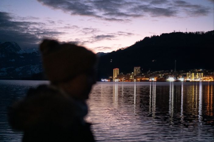 lake sunset black and purple, blurred person in foreground and city lights in background