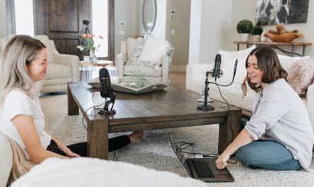 Zwei Frauen die gemeinsam am Boden sitzen und einen Podcast aufnehmen
