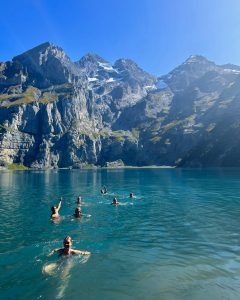 Seven people inside Lake Oeschinesee with the mountains in the background.