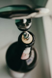 Inserting the corkscrew into the bottle of wine