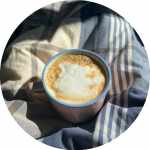 cup of coffee with steamed milk in the sunshine on a blanket