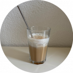 iced honey latte in a clear glass with a straw and milk foam on top