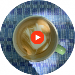latte art in a green cup on a blue tablecloth